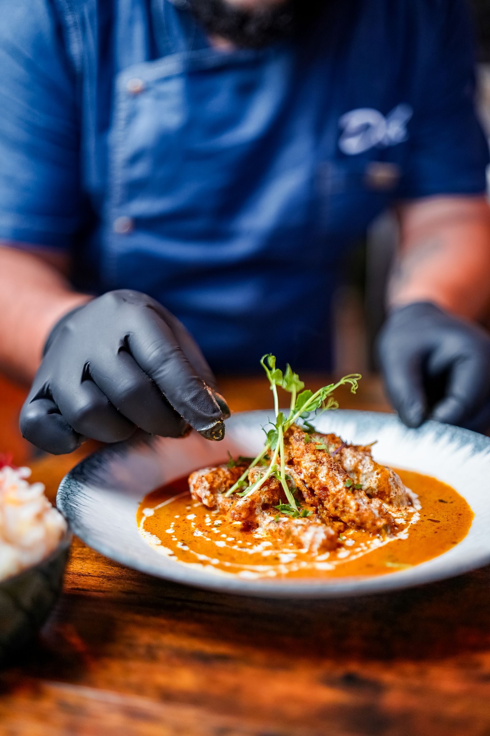 Butter chicken being plated at Deb's Bistro
